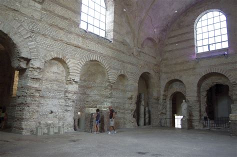 two people standing in the middle of an old building with stone arches and arched windows