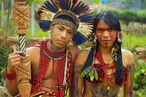 two people dressed in native american clothing posing for the camera