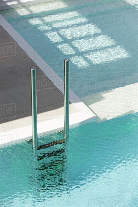 Swimming pool ladder at deep end separated from shallow pool by ledge ...