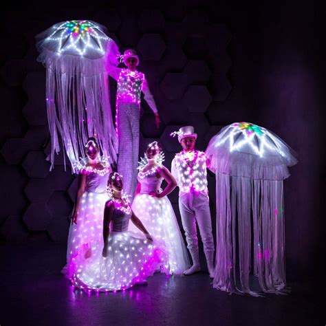 some people are dressed up as jellyfishs and one is wearing a costume with lights