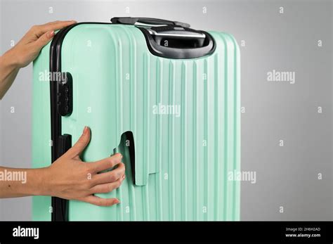 A woman demonstrates a broken suitcase on a white background. Damaged baggage during the flight ...