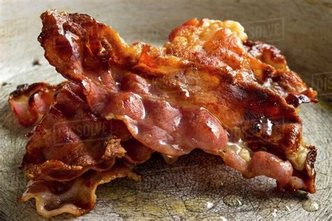 A stack of crispy rashers of bacon in a pan - Stock Photo - Dissolve