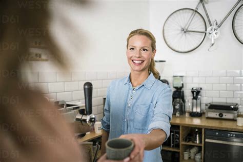 Young business owner in her coffee shop, serving coffee to a customer stock photo