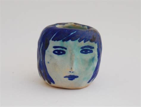 a blue and white vase with a face painted on the front, sitting against ...