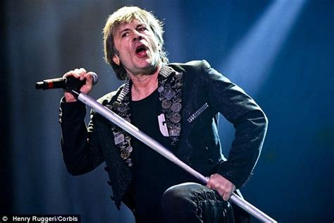 a man holding a large metal pole on top of his shoulder while singing ...