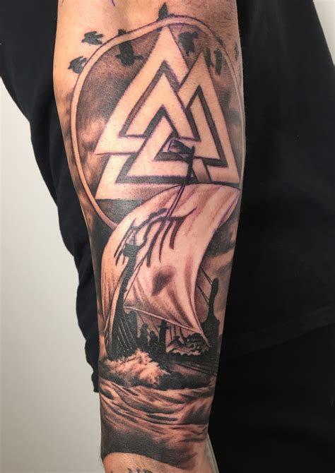 a man's arm with a ship on it and an illuminate triangle in the middle