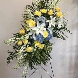 an arrangement of flowers is displayed on a stand in front of a white wall and floor