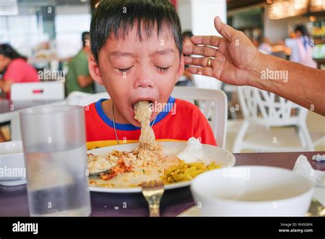 Boy puking on plate after having lunch meal in food court with helping ...