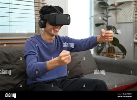 Cheery Asian man in VR headset holding imaginary steering wheel of ...