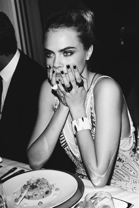 a black and white photo of a woman with her hands on her face while sitting at a table