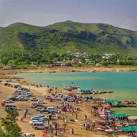 many cars are parked on the beach next to the water and mountains in the background