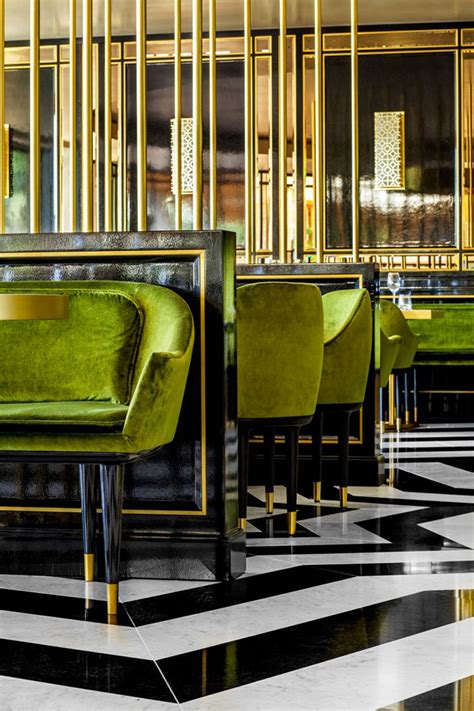 green velvet chairs and tables in a fancy restaurant with gold trim on the walls, black and ...