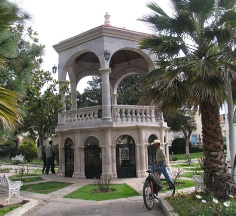 a person riding a bike in front of a gazebo with palm trees around it