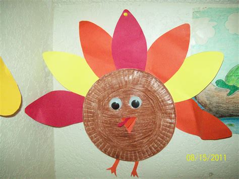 a paper plate turkey is hanging on the wall