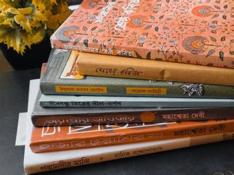 a stack of books sitting on top of a table next to a vase with flowers