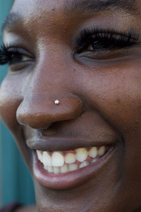 a close up of a person with a cell phone in their hand and a nose piercing