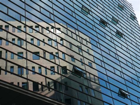 Reflection of brown building on blue glass facade free image download