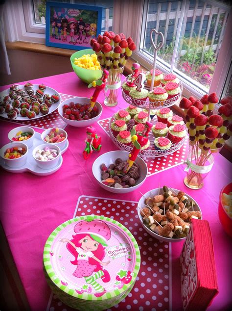 a pink table topped with lots of desserts and candy covered plates next to a window