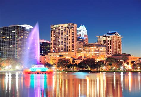 Orlando downtown skyline panorama over Lake Eola at night with urban skyscrapers, fountain and ...