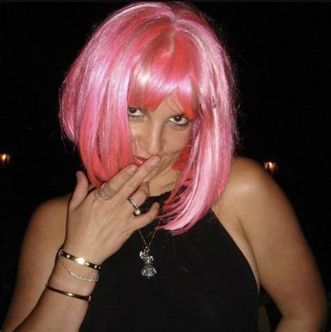 a woman with pink hair and rings on her fingers is posing for the camera while wearing a black top