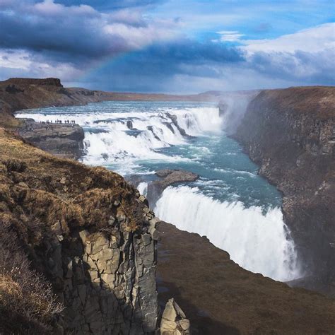 a rainbow shines in the sky over a large body of water that is ...