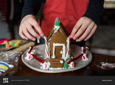 Boy constructing a gingerbread house with candy canes stock photo - OFFSET