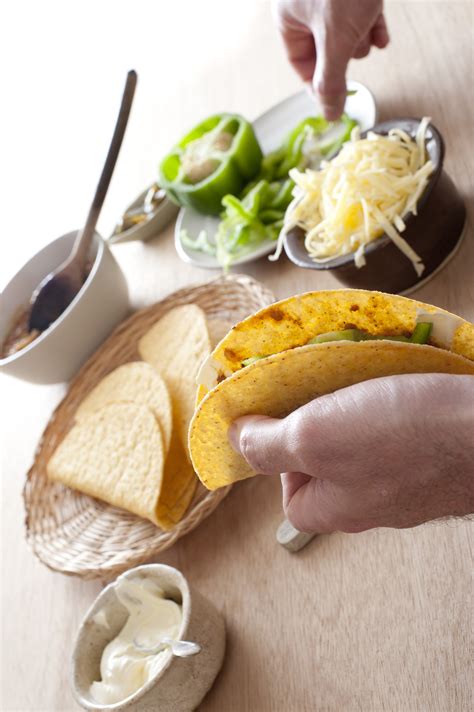 Man filling a taco with fresh ingredients - Free Stock Image