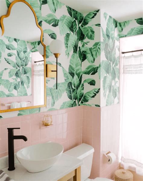 a bathroom with pink and green wallpaper has a mirror above the sink ...