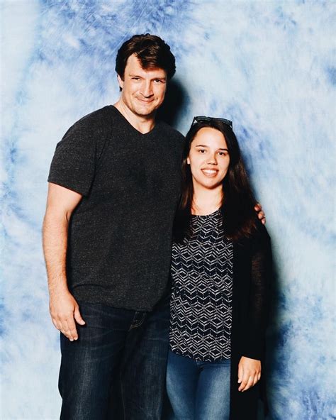 two people standing next to each other in front of a blue background