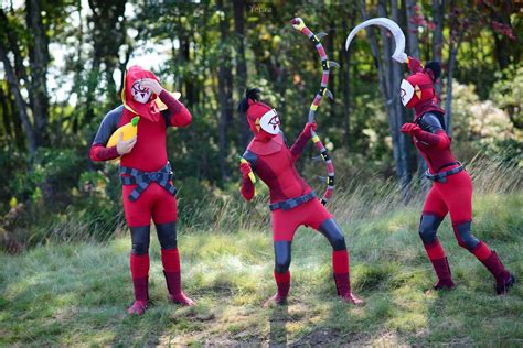 three people in red and black costumes are playing with arrows