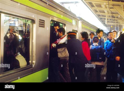 Asia Japan Tokyo Shinjuku station rush hour crowded crowds commuters. Train pushers push as many ...