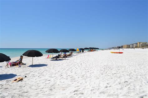 the beach is lined with umbrellas and lounge chairs for people to sit in it