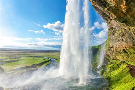 Seljalandsfoss Waterfall in Iceland surrounded by cliffs and green slopes