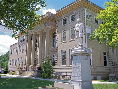 a statue in front of a large building with columns on the sides and a lawn