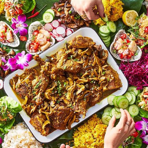 two hands reaching for food on a platter surrounded by various ...