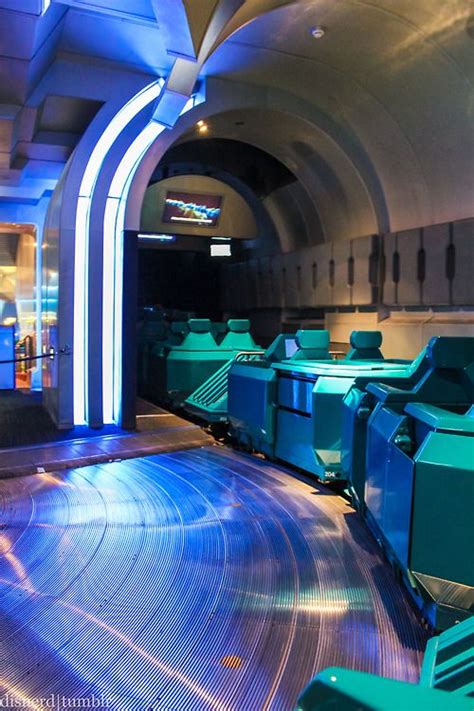 the inside of a train station with blue and green lights on it's walls