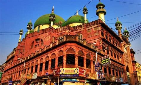 an old building with green domes and people walking on the street in front of it