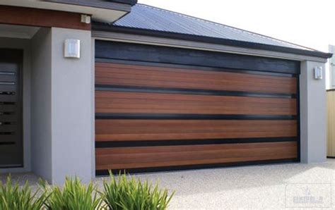 a house with a large wooden garage door in front of it and two plants ...