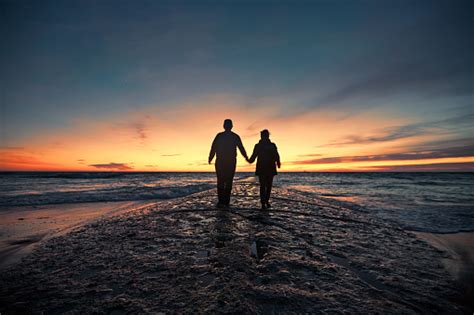 Senior Couple Walking From Seashore At Sunset Stock Photo - Download ...