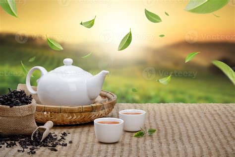 Warm cup of tea with teapot, flying green tea leaves in the air and ...