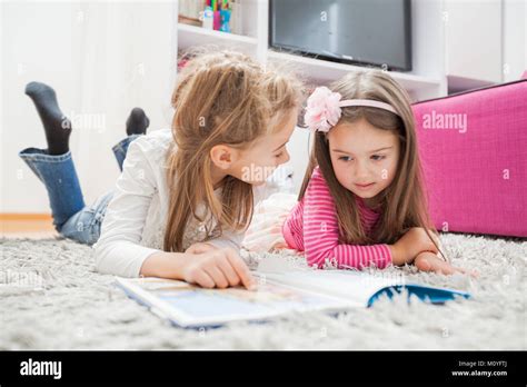 Two Little girl read book, lying on floor at home Stock Photo - Alamy