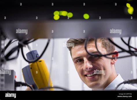 Smiling technician using digital cable analyzer on server Stock Photo ...