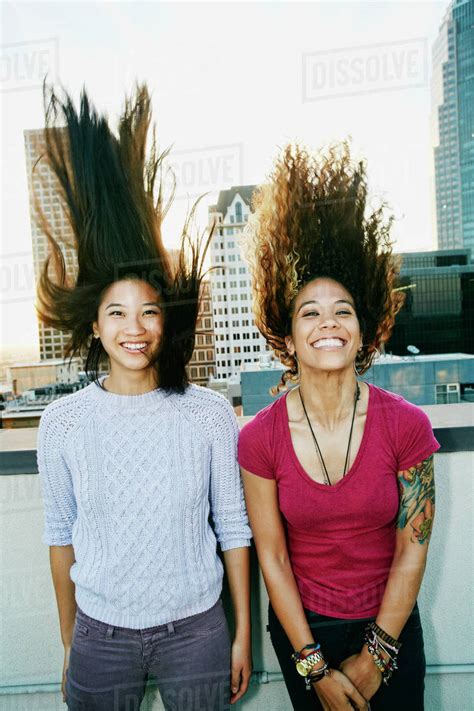 Women tossing their hair on urban rooftop - Stock Photo - Dissolve