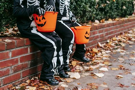 Children in Halloween costumes resting on fence with jack o lantern buckets · Free Stock Photo