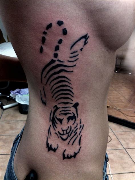 a black and white tiger tattoo on the side of a woman's lower back