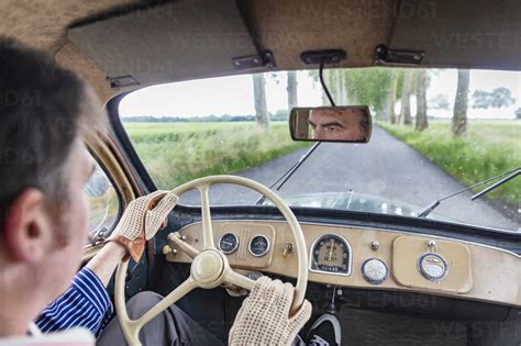 Man driving vintage car on country road stock photo