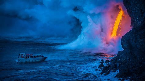 A lava flow hits water as a tour boat passes, Hawaii Volcanoes National ...