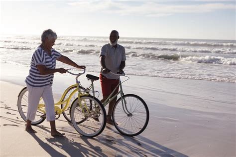 Premium Photo | Happy senior african american couple with bicycles walking together on the beach ...