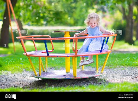 Happy laughing child, beautiful little toddler girl having fun on a playground enjoying a swing ...