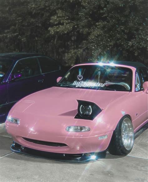 a pink car parked next to other cars in a parking lot